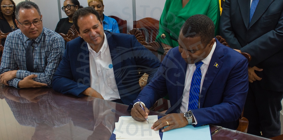 Minister of Energy and Water Resources Wilfred Abrahams (right), signing Government’s Energy Efficient Retrofit of Public Sector Smart Energy Programme agreement, as Chief Executive Officer of Caribbean LED Lighting Inc (centre), and Managing Director of the Barbados Light & Power Ltd Roger Blackman (left) look on.