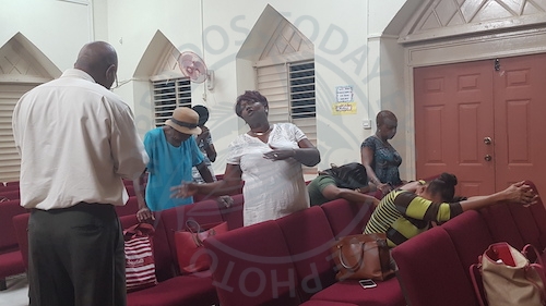 Pastor David Daniel (left) and Maxine Parris (in white) join other members of the church in prayer.