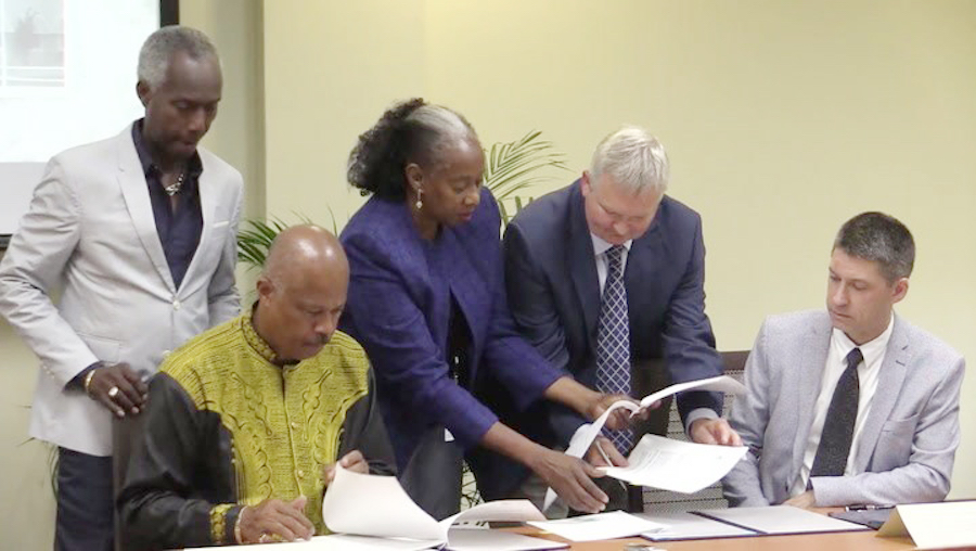 Sir Hilary Beckles (second from left) and  Dr David Duncan (right) signing the MOU today.